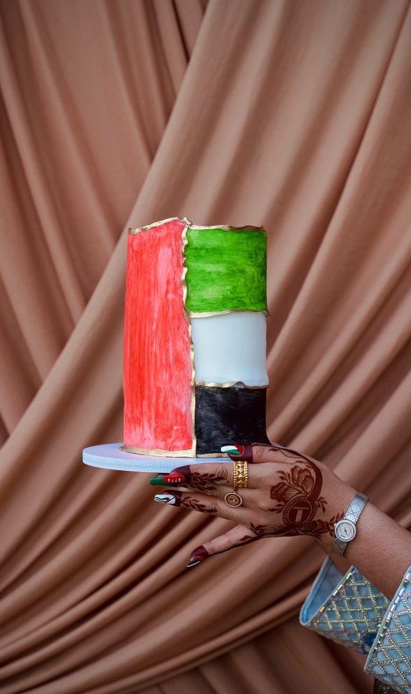 National Day cake UAE with vibrant colors representing the UAE flag, held beautifully by a hand