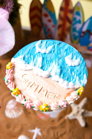 Floral beach cake dessert with blue ocean waves and summer theme decorated with pink and yellow flowers