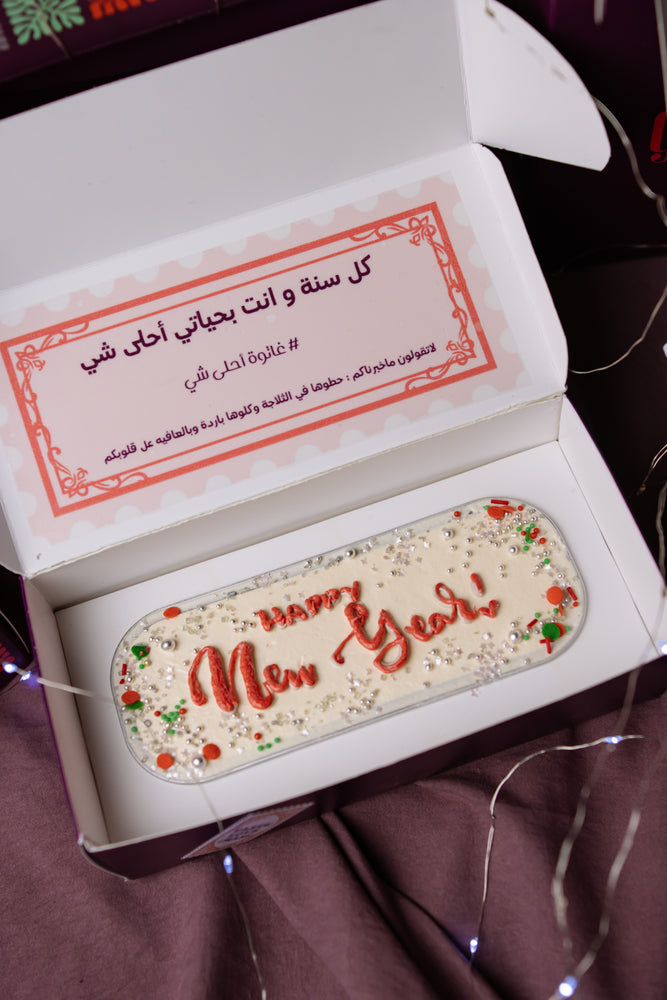Gateau Gourmet Cafe artisan loaf cake decorated with Happy New Year in red icing and festive sprinkles