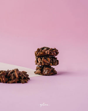Stack of Gateau Gourmet Cafe artisan nutty chocolate clusters on a pink background