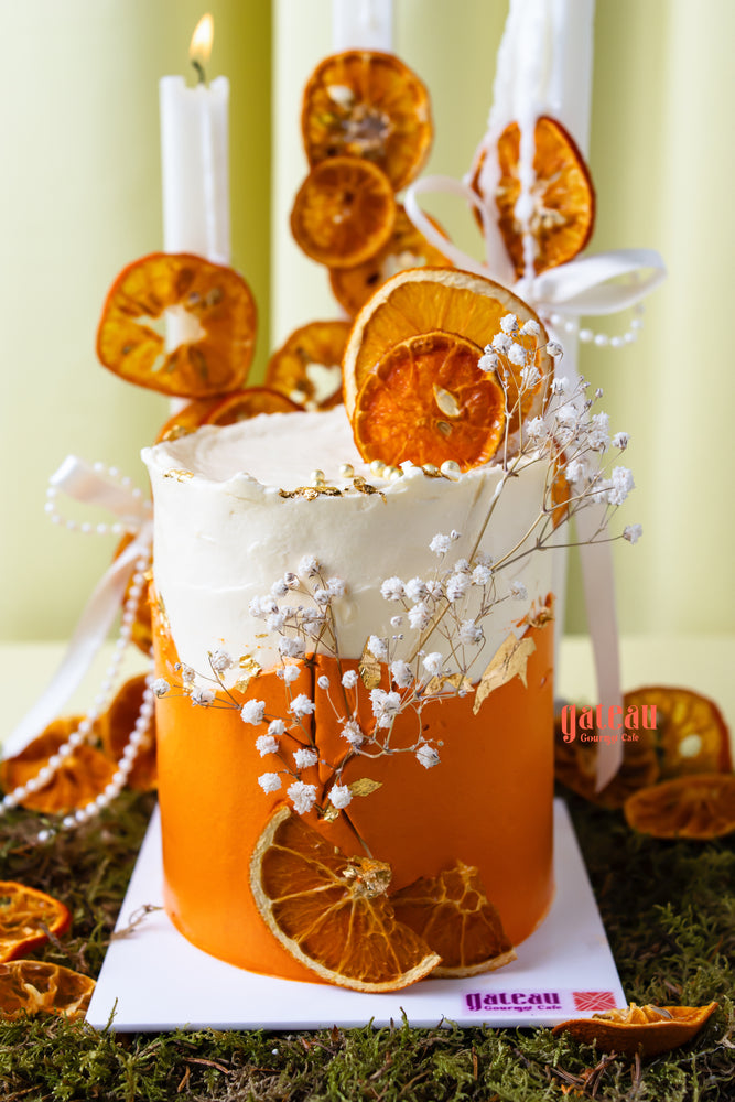Artisan orange summer celebration cake by Gateau Gourmet Cafe decorated with dried orange slices and white flowers