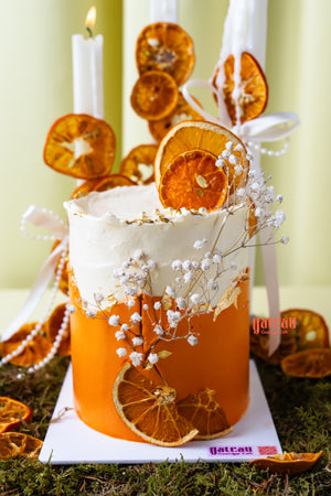 Artisan orange summer celebration cake by Gateau Gourmet Cafe decorated with dried orange slices and white flowers