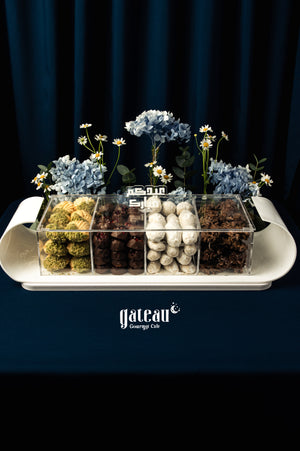 Assorted Arabic treats w arrangement in a clear container with flowers from Gateau Gourmet Cafe