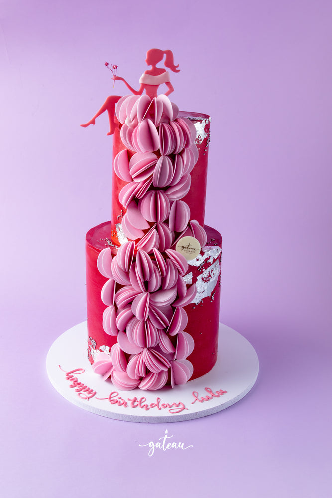 Elegant Barbie birthday cake with two-tier pink and red design and decorative doll topper