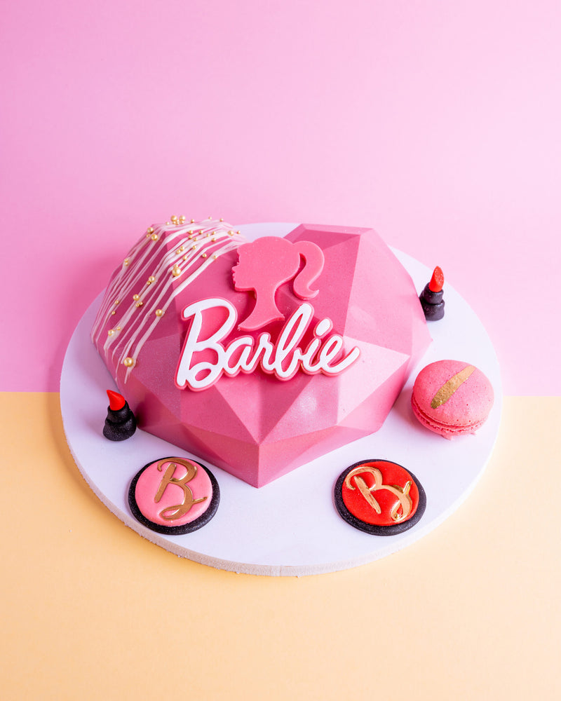 Pink geometric Barbie theme birthday cake with Barbie silhouette, macarons, and lipstick decorations