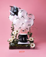 Black & White Graduate Cake Design with Arrangement featuring fondant graduation cap and decorative flowers