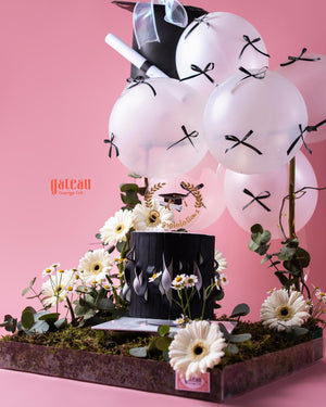 Black & White Graduate Cake Design with Arrangement featuring balloons and floral accents for celebrations