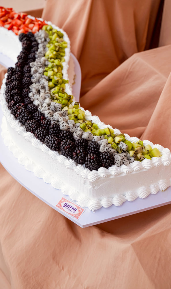 Curve sheet cake from Gateau Gourmet Cafe decorated with fresh fruits including strawberries, kiwi, and blackberries
