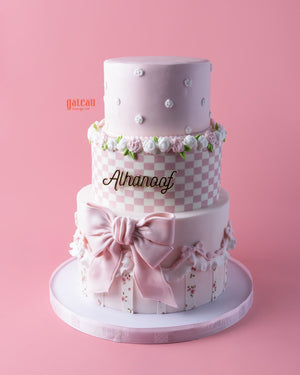 Melody-character-cake in pink with floral decorations and elegant bow from Gateau Gourmet Cafe