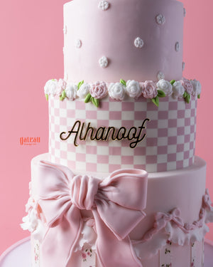 Elegant melody-character-cake with pink layers, floral decorations, and a satin bow from Gateau Gourmet Cafe