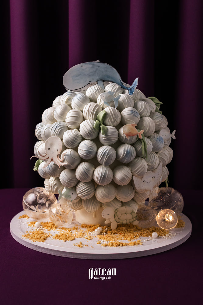 Whale truffle tower decorated with sea creatures and edible pearls in a whimsical design