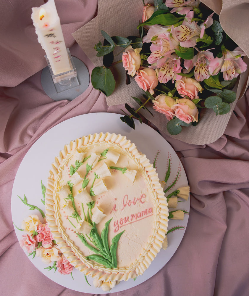 Elegant cake with floral cream design featuring a message of love and decorated flowers