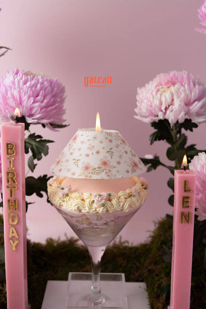 Elegant cake with flower arrangement designed for birthdays, featuring pink accents and decorative candles