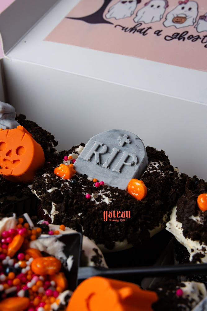 Creepin it real cupcake with spooky decorations, orange sprinkles, and a tombstone on top