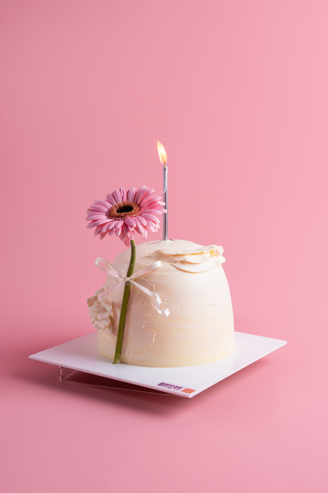 Cream Cake in Dome Shape with white frosting, pink flower, and lit candle by Gateau Gourmet Cafe