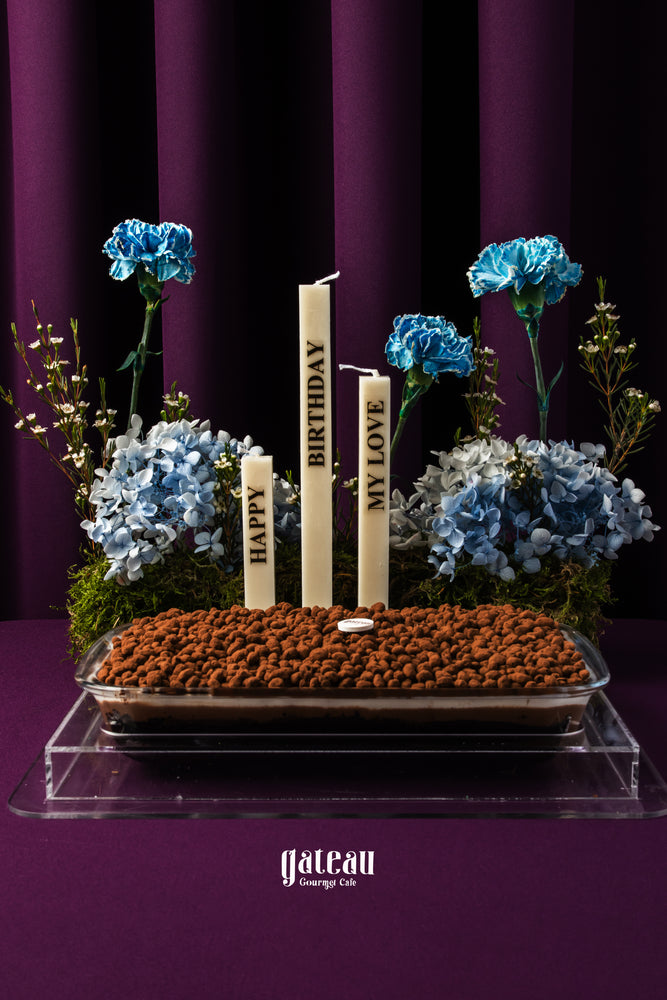 Crunch chocolate cake with flowers, featuring decorative candles and elegant floral arrangement