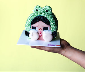 Gateau Gourmet Cafe CRYBABY character birthday cake with green frog hat design held on hand