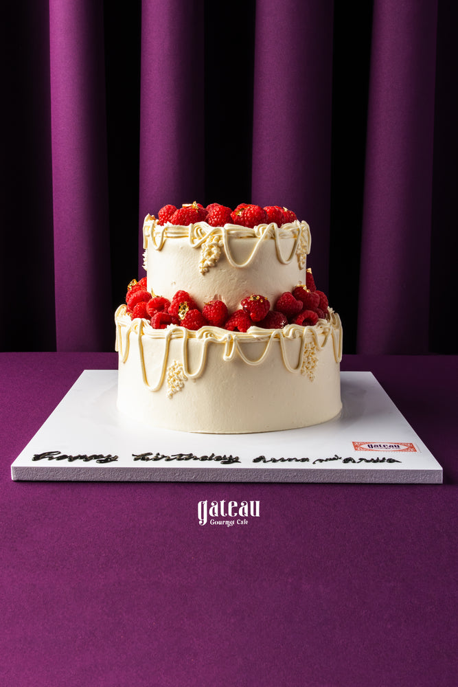 Gateau Gourmet Cafe custom birthday cake with berries featuring two tiers and white frosting with berry decorations
