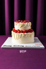 Gateau Gourmet Cafe custom birthday cake with berries featuring two tiers and white frosting with berry decorations