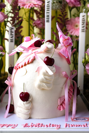 Custom cake with floral arrangement featuring pink decorations and cherries by Gateau Gourmet Cafe