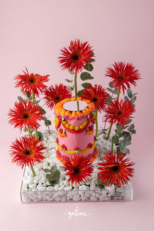 Gateau Gourmet Cafe custom floral cake design with vibrant red flowers and decorative icing on a pink background