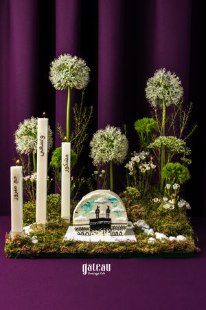 Gateau Gourmet Cafe custom Hajj themed cake with white candles and floral decorations on a green base