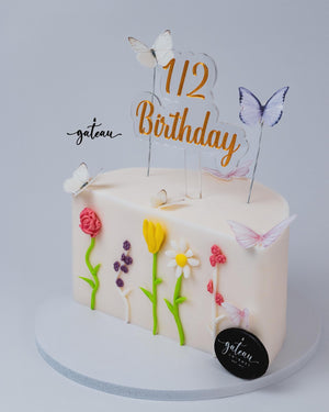 Gateau Gourmet Cafe custom half cake design with floral decorations and butterfly toppers for 1/2 birthday