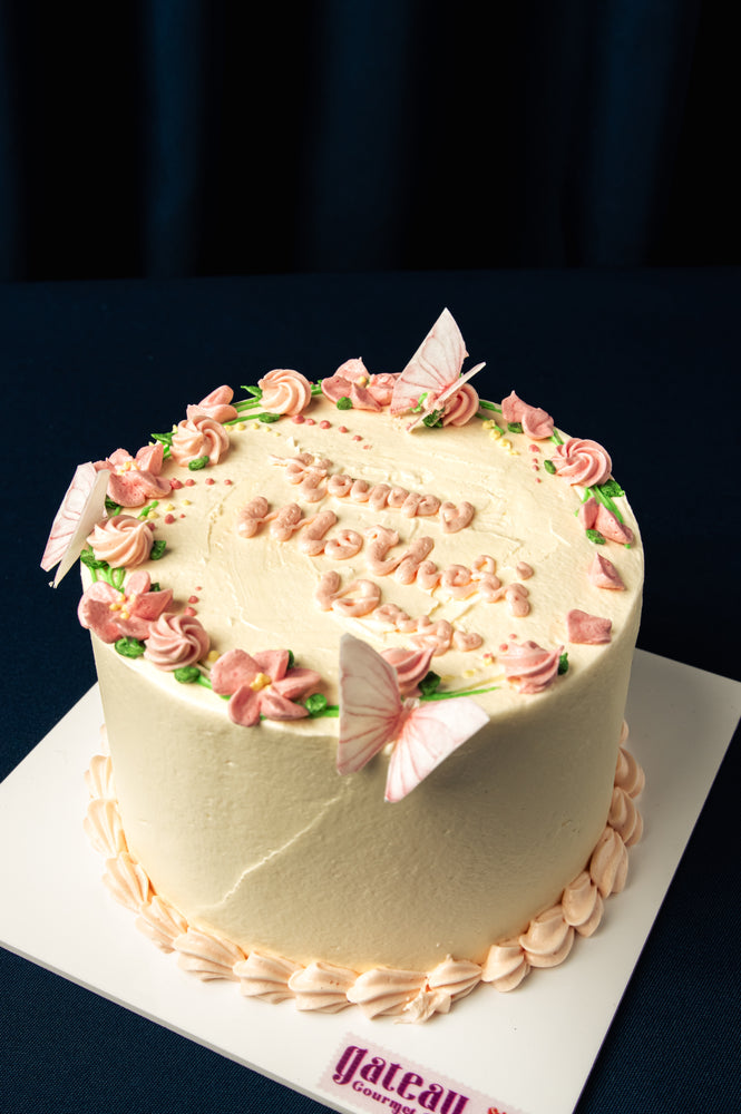 Gateau Gourmet Cafe custom Mother’s Day cakes with pink floral decorations and butterfly accents on white frosting