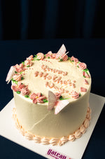 Gateau Gourmet Cafe custom Mother’s Day cakes with pink floral decorations and butterfly accents on white frosting