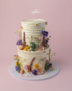 Elegant two-tier white wedding cake decorated with fresh flowers from Gateau Gourmet Cafe custom wedding cakes near me