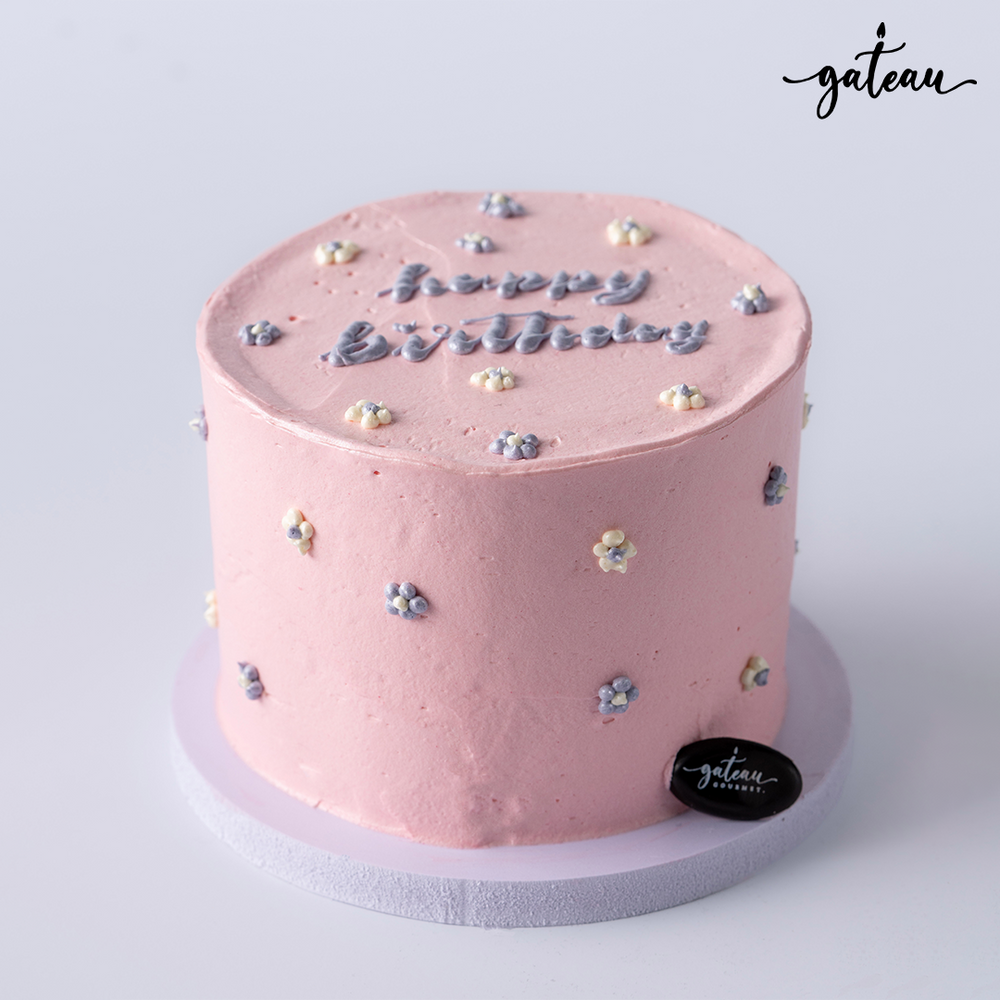 Pink birthday cake for girls with small floral decorations and happy birthday message