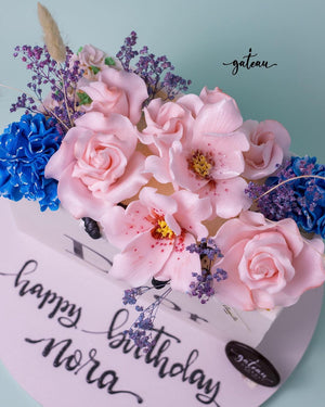Elegant dior-gift-cake adorned with pink and blue flower decorations for a birthday celebration
