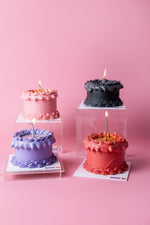 Four colorful edible glitter cake online options from Gateau Gourmet Cafe with lit candles on pink background