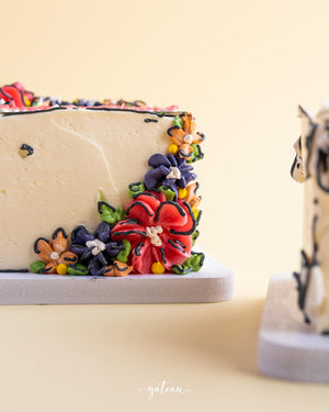 Gateau Gourmet Cafe mirror cake for special occasions with colorful floral icing decoration on creamy frosting
