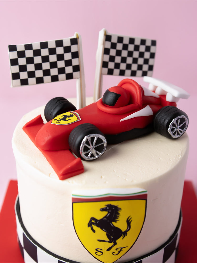 Ferrari theme cake with a red race car topper and checkered flags, perfect for car enthusiasts