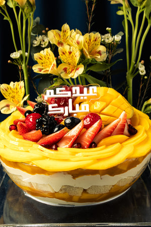 Festive Eid dessert mango-fruit-bow from Gateau Gourmet Cafe topped with fresh fruits and decorative text