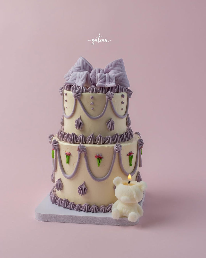 Fionka cake for special occasions by Gateau Gourmet Cafe decorated with purple bows and a teddy bear candle