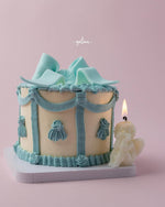 Fionka celebration cake by Gateau Gourmet Cafe decorated with blue icing and a lit angel candle