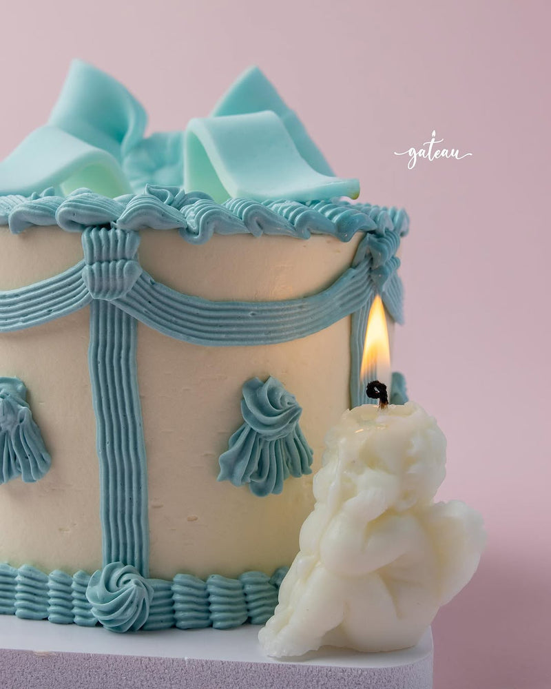 Fionka celebration cake by Gateau Gourmet Cafe with light blue decorative icing and a white angel-shaped candle