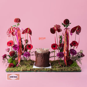 Gateau Gourmet Cafe chocolate cake with intricate floral cake decor featuring vibrant flowers and ribbons on moss base