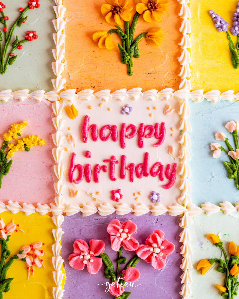Floral checkered box cake decorated with colorful flowers and a happy birthday message for festive celebrations