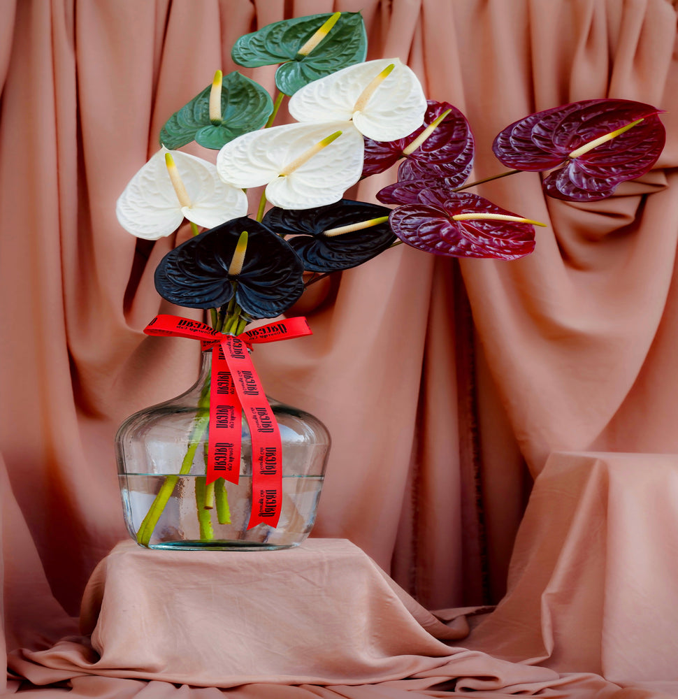 Elegant National Day flower arrangement in a glass vase with colorful anthurium blooms and a decorative ribbon