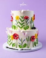 Two-tier flower decorated cake with colorful icing flowers and butterflies from Gateau Gourmet Cafe