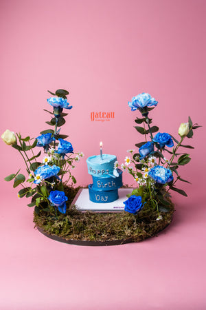 3 Layers Nano Cake with Candle in blue surrounded by blue and white flowers on moss base by Gateau Gourmet Cafe