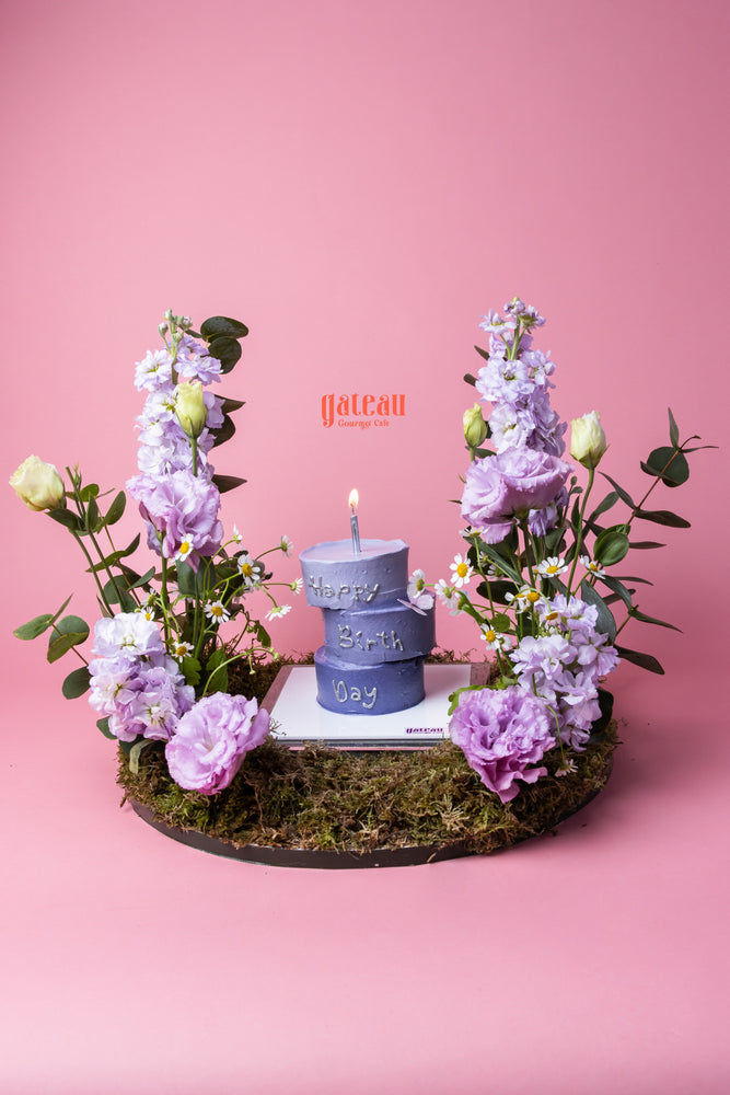 3 Layers Nano Cake with Candle in purple surrounded by flowers on a moss base by Gateau Gourmet Cafe