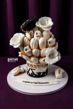 Graduation-themed cake featuring 53 Bites of Buttery and light Madeline decorated with flowers and a cap
