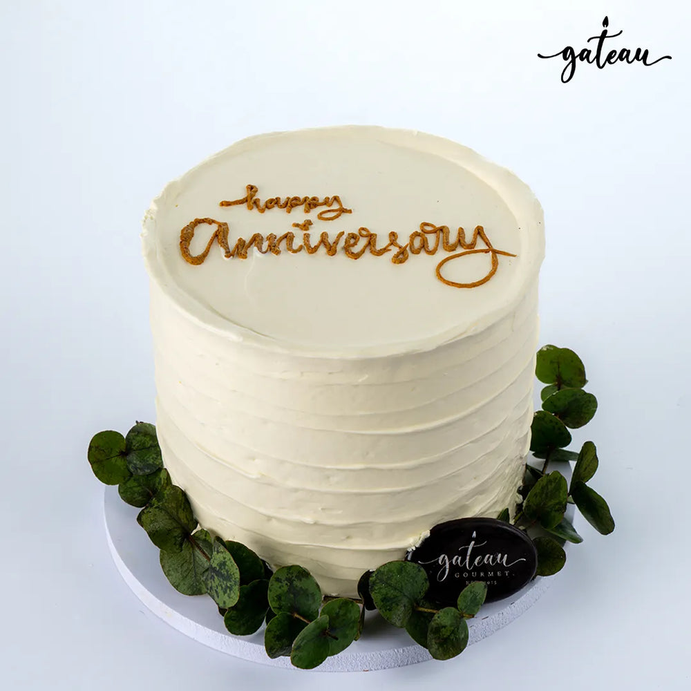 Gateau Gourmet Cafe white frosted anniversary cake with happy anniversary text and greenery decoration anniversary cake delivery