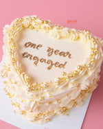 Anniversary heart shape cake with white frosting and gold pearl decorations by Gateau Gourmet Cafe