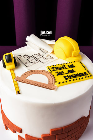 Architect themed cake with yellow hard hat, blueprint, measuring tape, and protractor decorations
