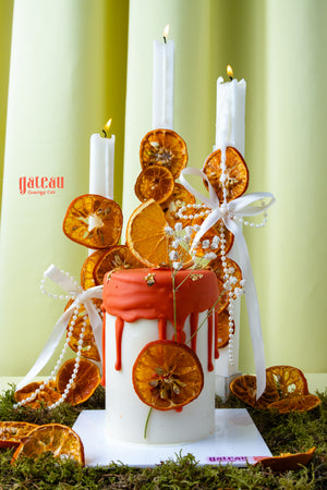Artisan cakes for special occasions by Gateau Gourmet Cafe featuring white cake with orange decoration and candles